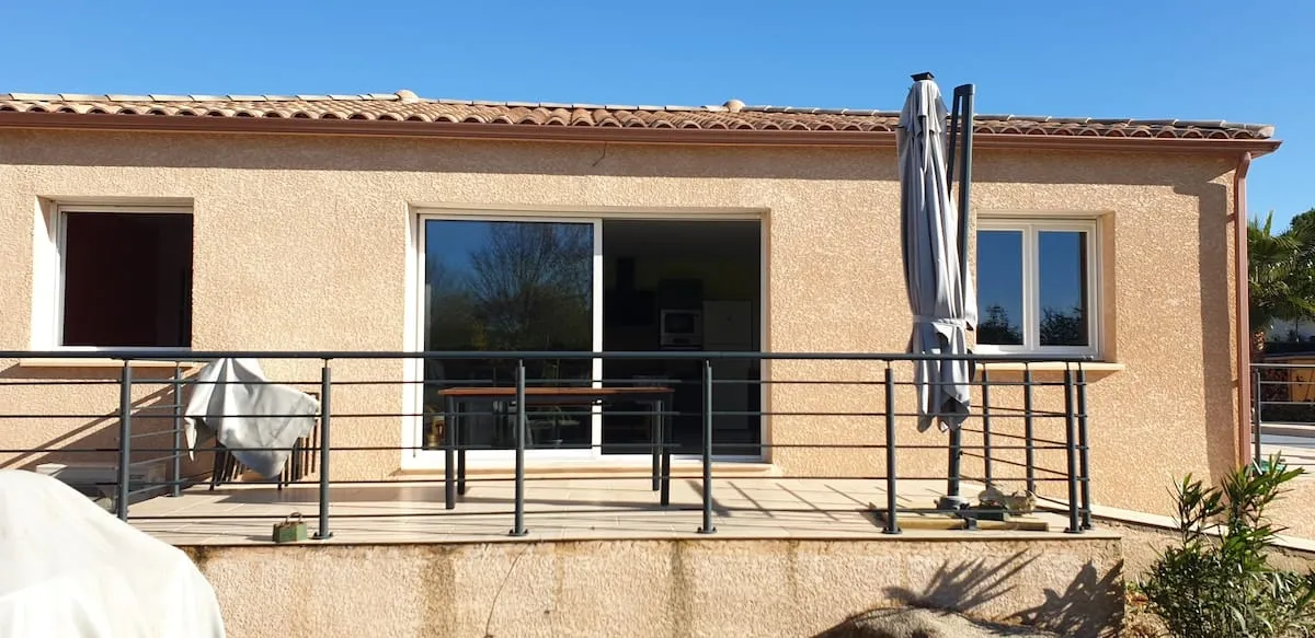 Façade de la maison avec terrasse ensoleillée sous un ciel bleu méditerranéen