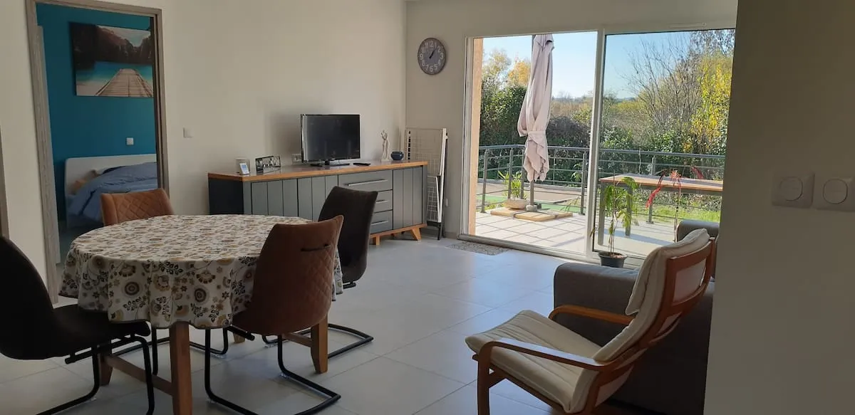 Salon lumineux avec accès direct à la terrasse via une grande baie vitrée